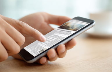 Photographie d'une personne lisant un article de presse sur un téléphone portable